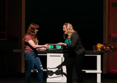 Scene from Freaky Friday: ELLIE and KATHERINE argue while each holds on to the hourglass