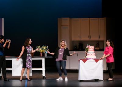 Scene from Freaky Friday: In the Blake family kitchen, LOUIS is taking photos, DANIELLE is recording an interview with KATHERINE, and TORREY wheels in the cake.